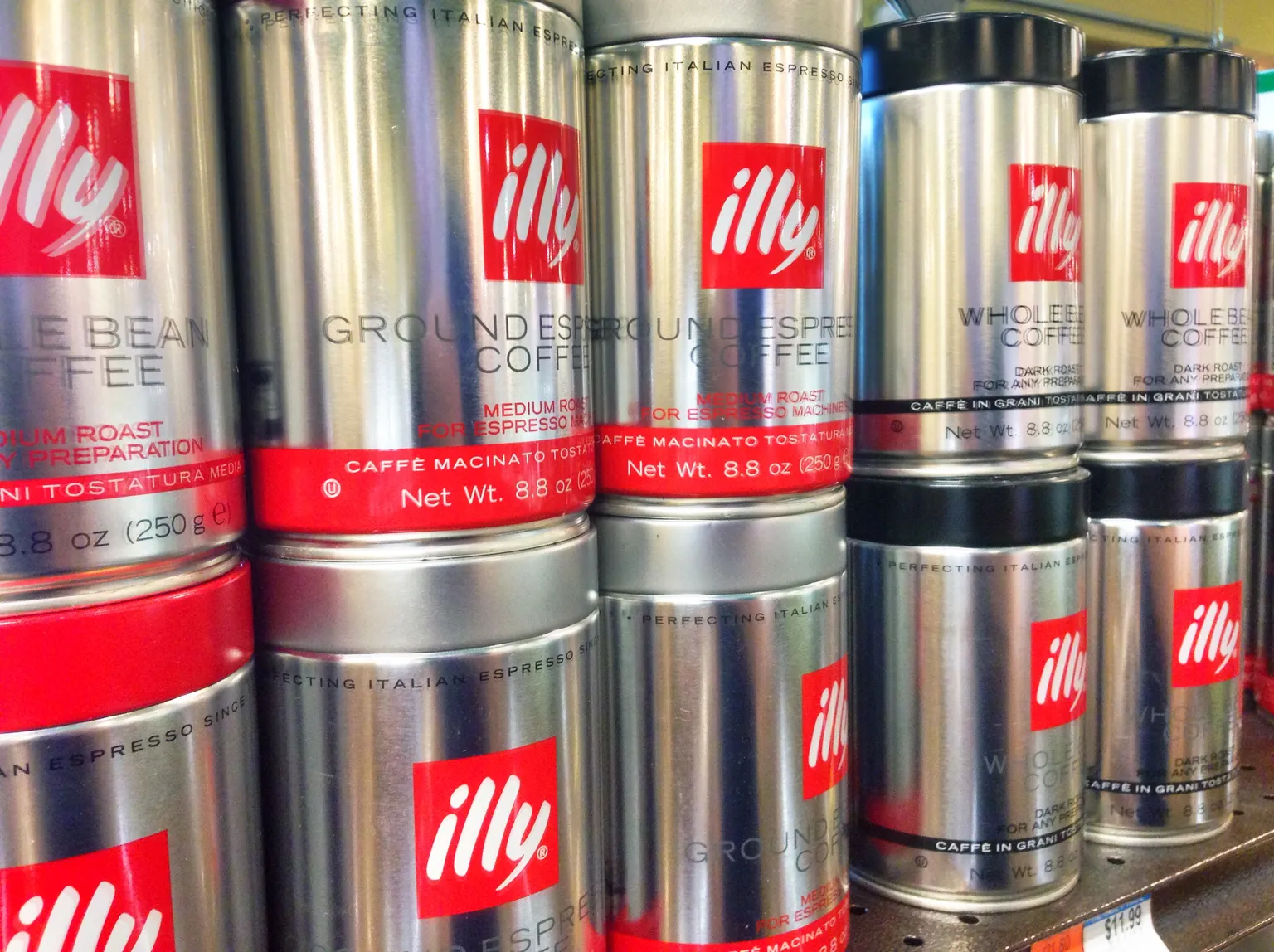 不同格式的 illy 咖啡罐排列在一起，可見咖啡豆與研磨粉標示